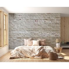 a bedroom with a brick wall and wooden flooring is shown in this image, there are several pillows on the bed