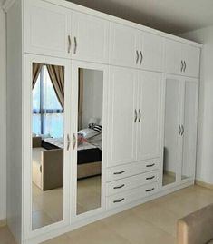 a large white closet with mirrored doors and drawers in the middle of an empty room