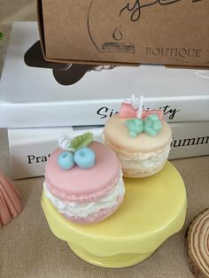 two small cakes sitting on top of a yellow cake stand next to a stack of books