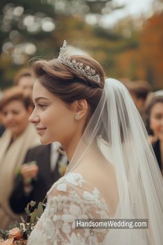 a woman in a wedding dress with a veil on her head and people behind her