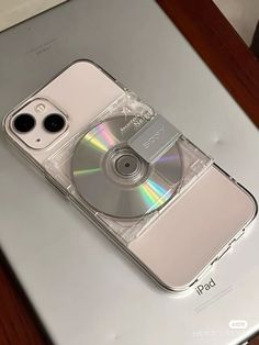 an iphone is sitting on top of a laptop with a cd in the back case