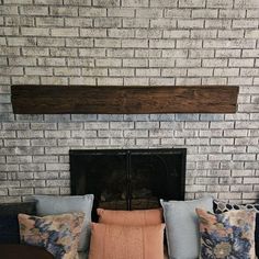 a living room filled with furniture and a fire place under a brick wall next to a fireplace