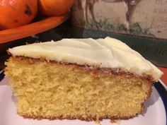 a piece of cake with white frosting on a plate next to some oranges