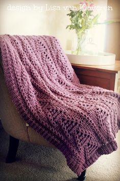 a purple crocheted blanket sitting on top of a chair