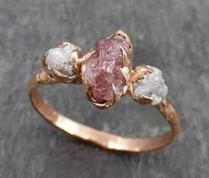 a gold ring with three rough diamonds on it