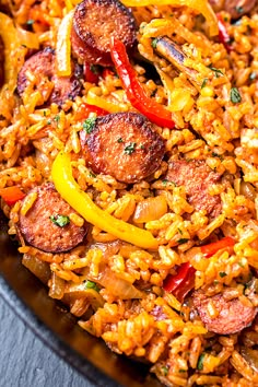 a plate full of rice with sausage and peppers