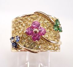 a gold ring with three different colored stones on the front and center, set in 18k yellow gold