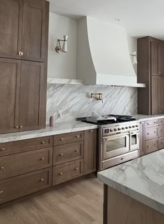 a kitchen with marble counter tops and wooden cabinets, along with stainless steel oven hoods