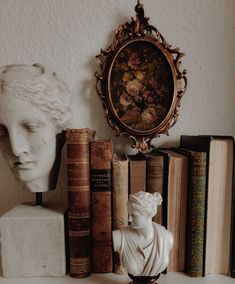 a white busturine sitting on top of a table next to books and a framed picture