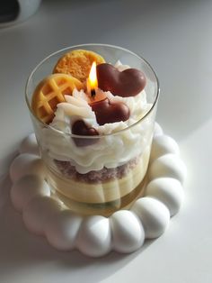 a small glass bowl filled with food on top of a white plate next to a lit candle