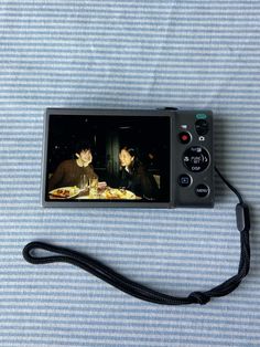 a digital camera sitting on top of a bed next to a black corded phone