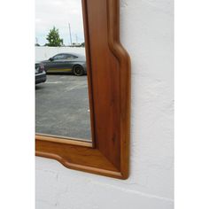 a car is seen in the reflection of a mirror on a white wall with a wooden frame