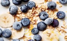 blueberries, bananas and granola on a white surface