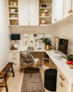 a home office with white cabinets and wooden flooring is pictured in this image, the desk has an area rug on it