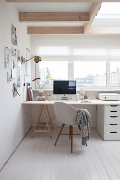 an office with white walls and wooden floors is pictured in this image, there are two computer screens on the desk