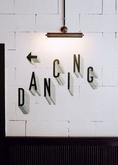 a white brick wall with the words dancing projected on it and an arrow pointing up