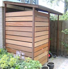 a wooden shed sitting in the middle of a yard with potted plants around it