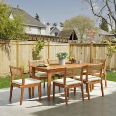 a wooden table with four chairs and a potted plant on top of the table