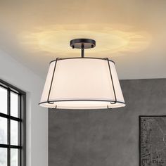 a light fixture with a white shade hanging from it's ceiling in a living room