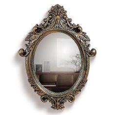 an ornate gold framed mirror hanging on the wall above a table with a vase in it