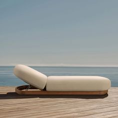 an outdoor chaise lounge on a wooden deck overlooking the ocean