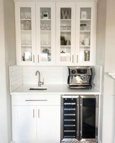 an empty kitchen with white cabinets and wood flooring in the center is seen from across the room