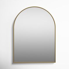 an arched mirror hanging on the wall in front of a white wall with a gold frame