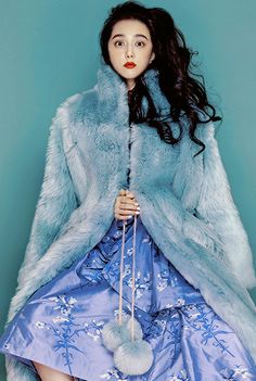 a woman in a blue dress and fur coat