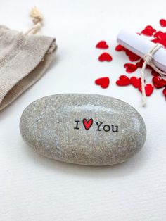 a rock with the word i love you written on it next to some red hearts