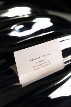 a close up of a wine bottle with a business card on the label that says embrace the you