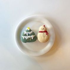 two small snowmen sitting on top of a white plate