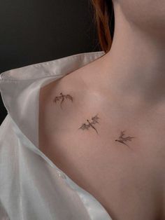 a woman's chest with three small birds on the left side of her chest