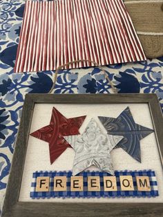 an american flag and some patriotic stars on a bed with the word freedom spelled in wooden letters