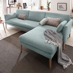 a living room with a blue couch and pillows on the floor, in front of a window