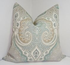 a decorative pillow is shown on a white surface with a light blue and beige paisley pattern