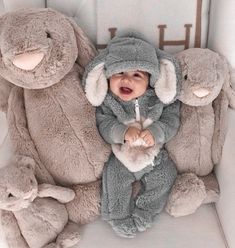 a baby is sitting in a crib with stuffed animals around him and smiling at the camera