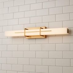 a bathroom light that is on the side of a brick wall with white bricks behind it