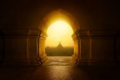 an archway leading to a large building with a sunset in the background