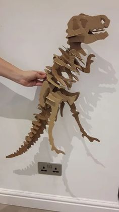 a person holding up a paper cut out of a dinosaur