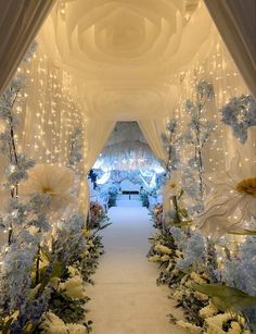 an archway decorated with flowers and lights for a wedding ceremony at the end of a long aisle