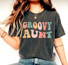 Groovy Aunt Shirt, Auntie Shirt, Family Groovy Shirts, New Aunt Gift, Hippie Floral Aunt Tee, Birthday Party Shirts, Family Matching Shirt We create custom t-shirts with great designs for everyone's liking. If you don't find the size or color you would like, please message us and we will be happy to accommodate! PRODUCT We use the finest premium Bella Canvas shirts for you, they are feather soft and very breathable with a good stretch. These t-shirts are known for their great quality and much loved by our consumers. SIZING This t-shirt comes in UNISEX sizing. It looks great on both men and women, but women are recommended to order a size down for a fitted look! Please refer the sizing chart to find your perfect fit! COLORS Colors on screen and the printed product may slightly vary due to s Casual Multicolor Shirt For Birthdays, Casual Multicolor Shirt For Birthday, Casual Tops For Fall Birthday, Graphic Print Tops For Birthday In Fall, Multicolor Letter Print Tops As Gift, Multicolor Graphic Print Tops As Gift, Multicolor Text Print Top As A Gift, Multicolor Text Print Top As Gift, Multicolor Text Print Tops As Gift