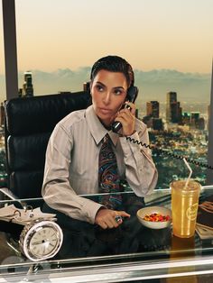 a woman is sitting at her desk talking on the phone and eating salad in front of her