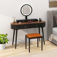 a desk with a mirror, stool and potted plant