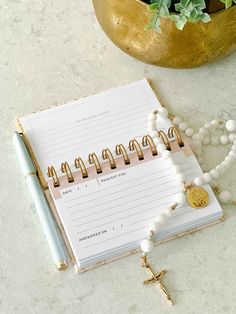 a notepad and pen sitting on top of a table next to a plant with beads