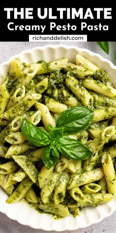 the ultimate creamy pesto pasta recipe in a white bowl with basil leaves on top