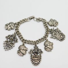 Vintage charm bracelet is silver tone metal with large heraldic charms. The charms are suits of armour helmets and shields. The armour helmet is about 7/8 inch top to bottom and the shield is about 1 3/5 inches top to bottom. This has a nice weighty feel and is unsigned. It is 7 inches long and a tiny bit over 1/4 inch wide. In excellent vintage condition. Find lots more vintage jewelry at Purple Daisy Jewelry! http://www.etsy.com/shop/purpledaisyjewelry Thanks a bunch for shopping for vintage j Silver Engraved Metal Charm Bracelet, Engraved Silver Metal Charm Bracelet, Vintage Silver Jewelry With Coat Of Arms, Antique Silver Metal Charm Bracelet, Armour Helmet, Filigree Bracelet, Daisy Jewelry, Vintage Charm Bracelet, Purple Daisy