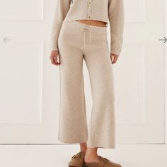 Meet The Wide Leg Sweater Pants In Oatmeal. Made Of A Merino Wool Blend, This Classic Sweater Pant Is Cropped, High-Waisted, And Has An Elastic Waist. An Added Drawstring Makes These Adjustable And An Easy Fit. Comfortable Enough To Lounge In Yet Polished Enough To Wear Out 45% Wool, 36% Viscose, 9% Nylon, 5% Cashmere, 5% Elastic Dry Clean Only Made In China Cozy Cream Bottoms For Spring, Cream Pants For Fall, Cozy Beige Pants For Fall, Cozy Beige Bottoms For Fall, Cream Pants For Loungewear In Fall, Neutral Pants For Loungewear In Fall, Neutral Pants For Fall Loungewear, Cream Pants For Fall Loungewear, Cozy Neutral Bottoms For Fall