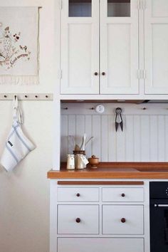 a kitchen with white cabinets and wooden counter tops