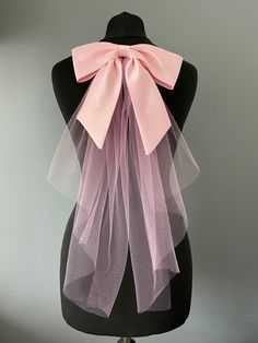 If you don't want a full veil how about this pretty pink satin hair bow with  and tulle veiling tails. A finishing touch that says bride but is a lot more modern.  The bow is 24cm long by 7cm  The silk tails measures 21cm to the longest point. With the tulle 46cm from the bow.  All mounted on a hair comb which can be slipped into your hair do and pinned into place. This lovely hair bow will go with loads of wedding dress styles even trouser suits and mini dresses and just a touch for colour for Bow Veil, Satin Hair Bow, Pink Hair Bow, Pink Hair Bows, Veil Wedding, Hair Do, Mini Robes, Wedding Veils, Look Vintage