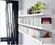 three white shelves with books and plants on them